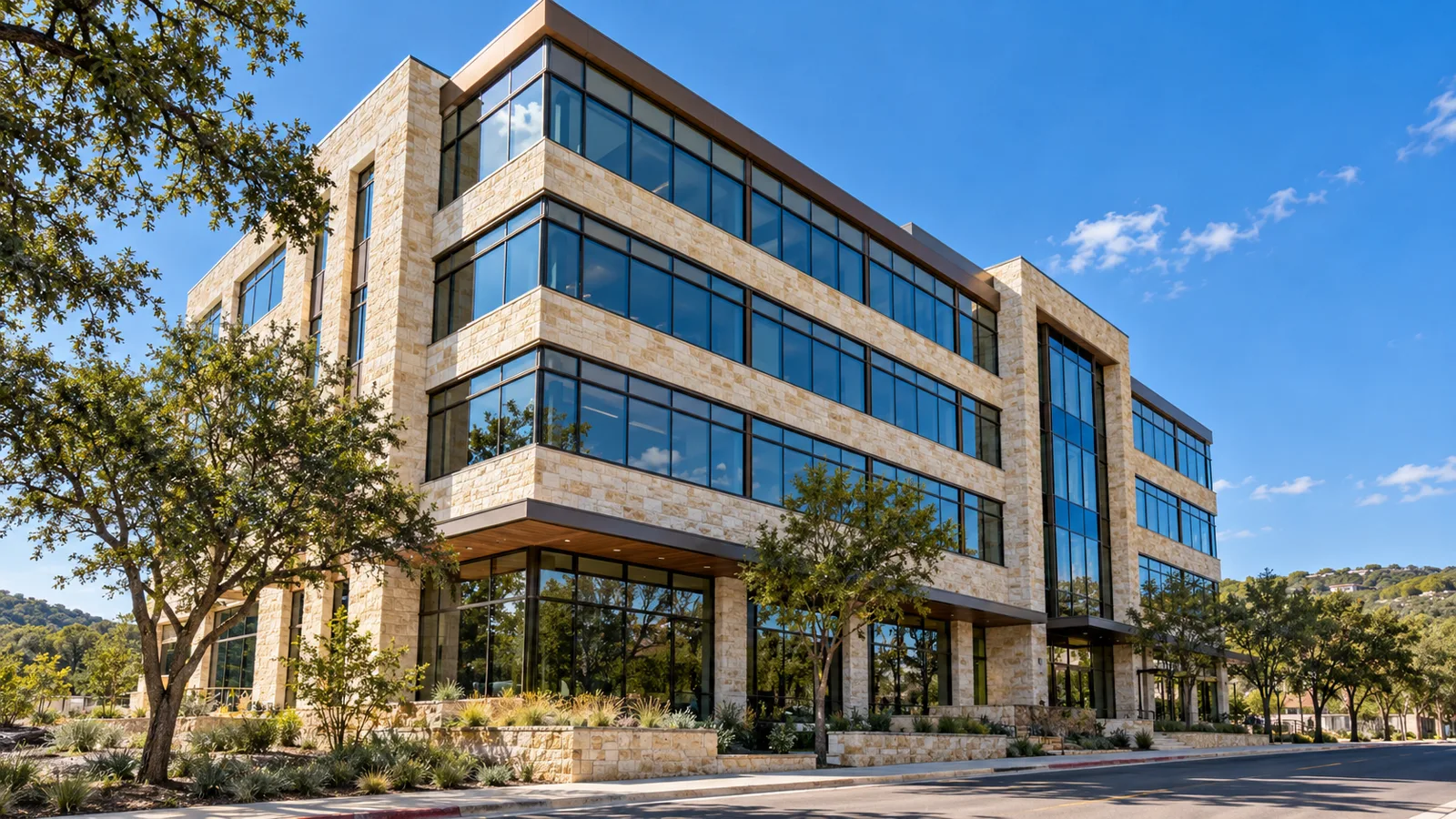 A four-storey Austin office building in limestone with new continuous ribbon windows in dark bronze frames under a blue sky