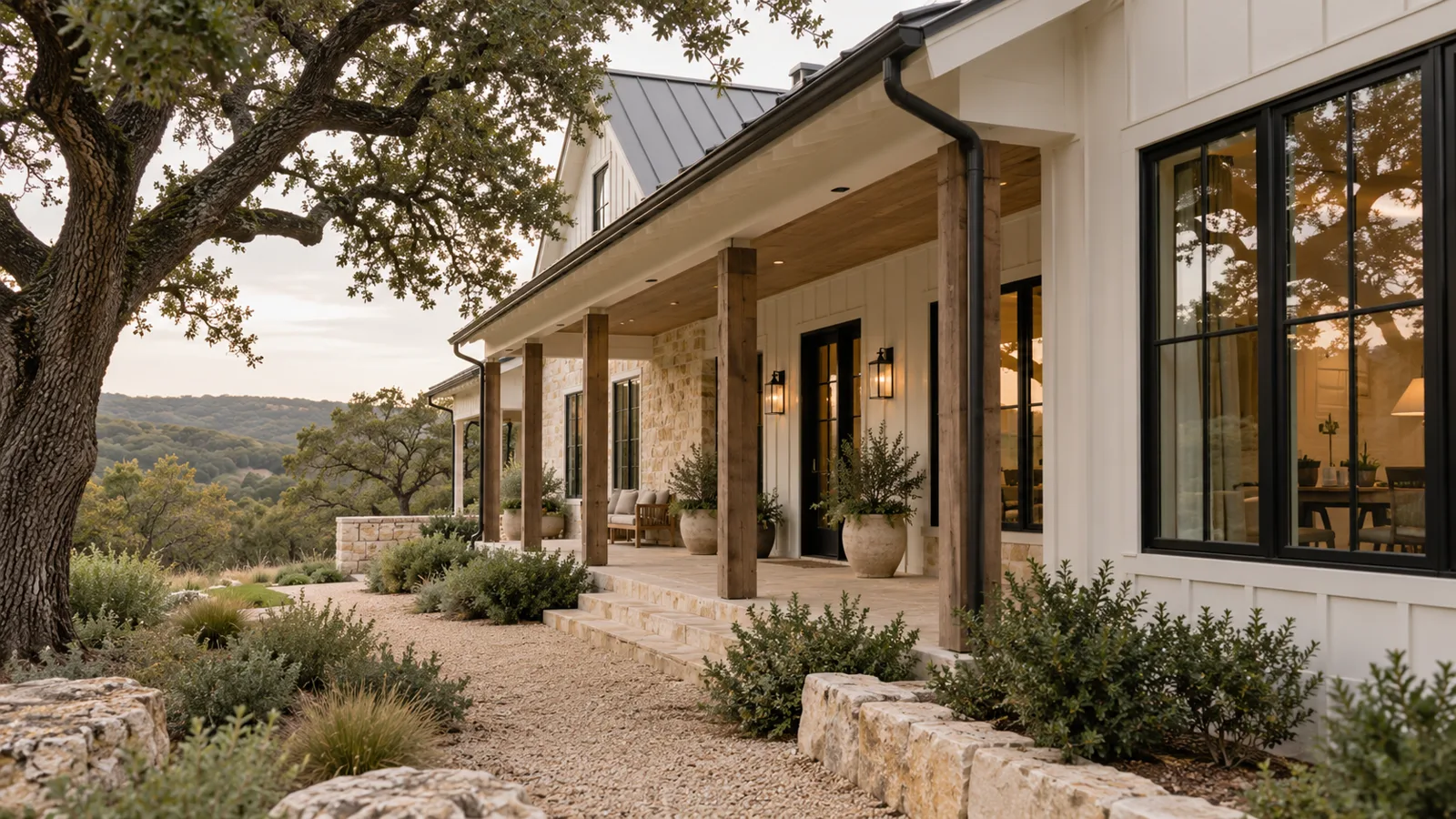 Black fiberglass windows on a white board-and-batten modern farmhouse near Austin with a covered porch and live oak
